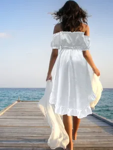 Back view of elegant white off-shoulder maxi dress with ruffles at the beach