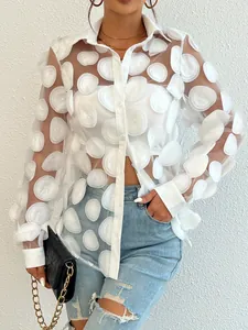 Détail d'une chemise en maille transparente blanche avec fleurs 3D.