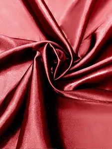 Gros plan sur un tissu satiné rouge foncé luxueux montrant sa texture lisse