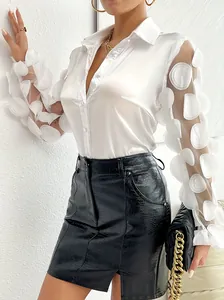 Dettaglio di un'elegante camicia bianca in raso con maniche in rete a fiori 3D e colletto.