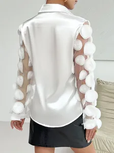 Primo piano di una camicia di raso bianco con applicazioni floreali su maniche in rete velata