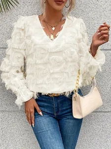 Gros plan sur ce chic chemisier blanc à manches longues et sa texture de plumes.