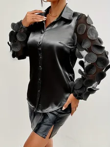 Dettaglio di una camicia in raso nero con maniche in mesh a fiori 3D uniche e colletto a rever
