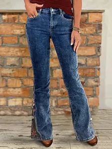 Detail of flared blue jeans featuring elegant floral embroidery and stretchy denim