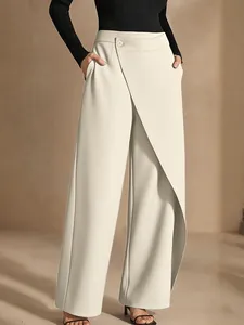 Detail of cream asymmetric wide-leg trousers showing elegant drape and waist button.