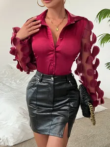 Dettaglio di una camicia bordeaux con maniche floreali e gonna in pelle nera.
