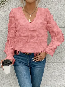 Vue détaillée de la blouse rose à manches longues avec franges de plumes et col en V chic.