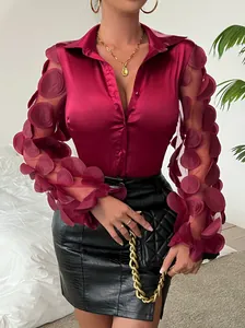 Dettaglio ravvicinato di camicia in raso bordeaux con maniche a sbuffo floreali 3D.