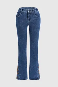 Detailed view of blue flared stretch denim jeans featuring colorful floral embroidery at the hem