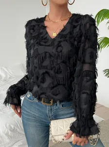 Vue détaillée de la blouse noire à col en V et manches longues à franges de plumes.