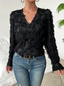 Détail d'une élégante blouse noire à col en V et manches longues avec texture à plumes.