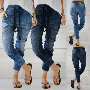 Detailed view of loose drawstring waist denim harem pants for women with tapered cuffs.