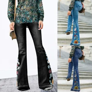 Close-up of floral embroidery on flared denim jeans with intricate stitching detail