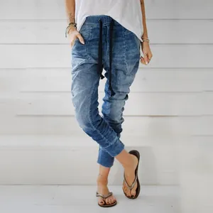 Women's loose fit elastic waist drawstring jeans with a faded wash and tapered leg detail.