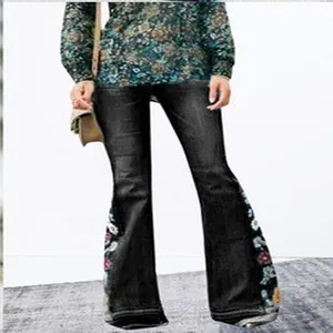 Close-up detail of women's flared denim jeans featuring colorful side floral embroidery.
