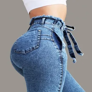 Close-up of high-waisted denim jeans featuring a raw frayed edge and matching tie belt.