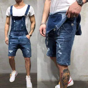 Gros plan détaillé d'une salopette en jean pour homme avec déchirures et boutons en métal.