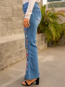 Detail view of stylish women's blue flare jeans featuring vibrant floral embroidery.