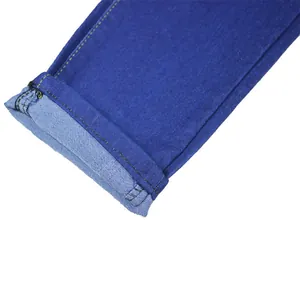 Macro view showing the rolled-up cuff detail and stitching on blue denim jeans