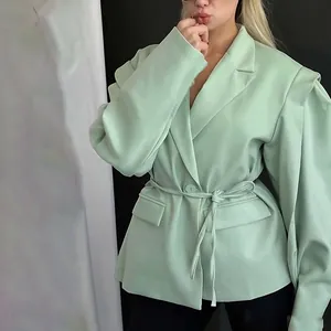 Vista detallada de una chaqueta blazer verde menta con cinturón, solapa y bolsillos.