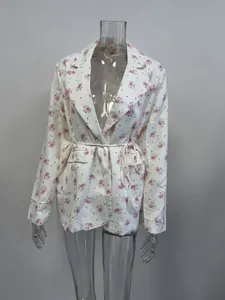 Vista detallada de la chaqueta con estampado floral, cuello solapa y lazo en cintura.