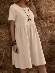 Vista detallada de un vestido holgado de algodón y lino beige con cuello redondo y bolsillos.