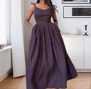 Elegant dark brown V-neck camisole maxi dress with a pleated skirt in a room setting