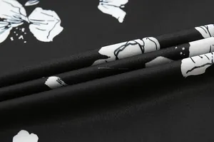 Close-up of black cotton fabric with white floral pattern and detailed weave texture.