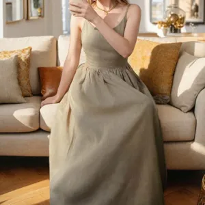 Detail shot of elegant high-waisted linen maxi dress with flowing skirt on sofa