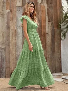 Side view of green floral tiered maxi dress with ruffled sleeves in a rustic outdoor setting.