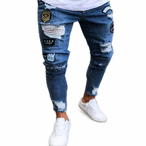 Men's slim-fit ripped jeans in light blue denim featuring decorative military badge patches