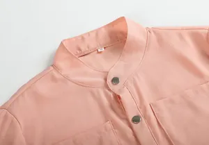 Gros plan d'une robe en mousseline pêche avec col mandarin et boutons-pression