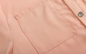 Détail d'une robe en mousseline rose montrant une poche et un bouton métallique argenté