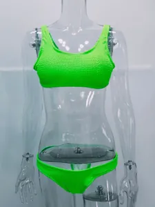 Detalle de un conjunto de bikini verde neón en tela rugosa mostrado sobre un maniquí