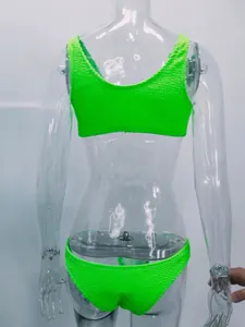 Vista posterior de un bikini de tela arrugada verde neón en un maniquí de plástico claro