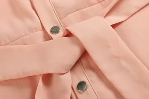Gros plan d'une robe en mousseline rose avec détails de boutons et texture de tissu