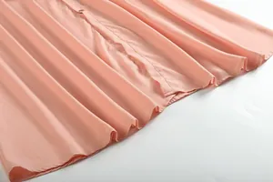 Vue détaillée de l'ourlet plissé et du tissu en mousseline douce d'une robe rose