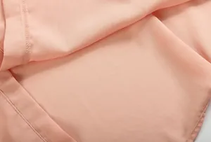 Gros plan sur un tissu en mousseline rose montrant la texture et les coutures