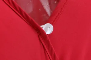 Close-up macro view showing V-neckline and white button detail on red cotton jumpsuit fabric