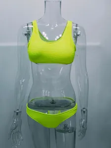 Detalle de conjunto de bikini amarillo neón en tejido arrugado sobre un maniquí