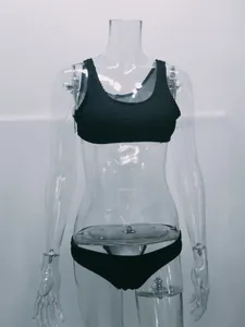 Detalle de un conjunto de bikini negro de tela rugosa presentado en un maniquí transparente.