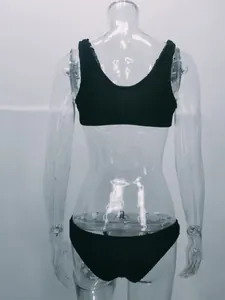 Vista posterior detallada de un bikini negro de tela rugosa en un maniquí transparente