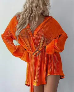 Detail of vibrant orange pleated long-sleeve shirt dress featuring a stylish waist belt.