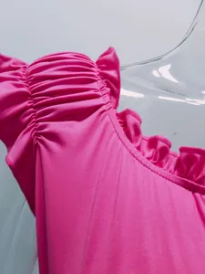 Detailed view of the ruffled shoulder and pleated neckline on a pink elegant summer dress