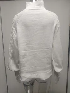 Detail of a white knitted sweater featuring lantern sleeves and a cozy high neck design