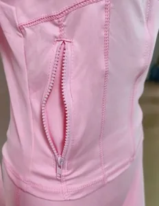 Détail macro d'une veste de yoga rose à séchage rapide avec poche zippée pratique
