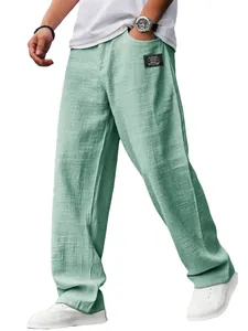 Detalle de pantalones de lino sueltos para hombre en verde menta con parche decorativo.