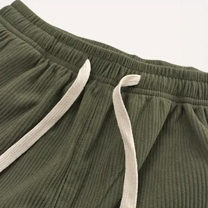 Nahaufnahme der olivgrünen Cordhose mit strukturiertem elastischem Bund und Kordelzug.