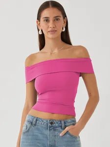 Model wearing a vibrant hot pink off-the-shoulder top with denim jeans