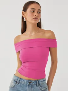 Model wearing a vibrant pink off-the-shoulder slim fit top with blue denim jeans